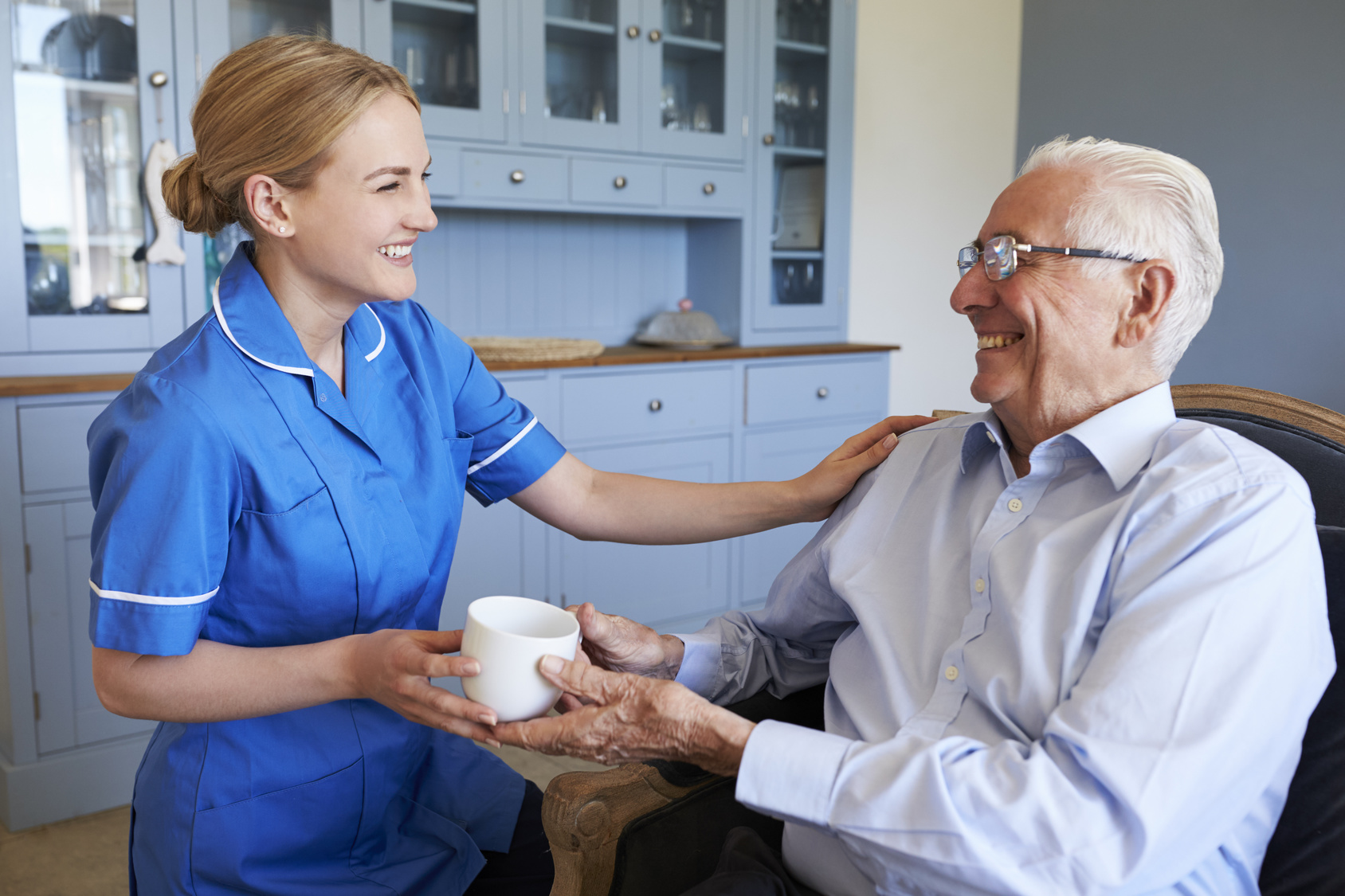 Caregiver handing senior cup of tea