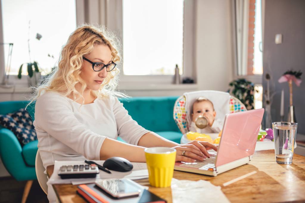Mother with baby using laptop at home office