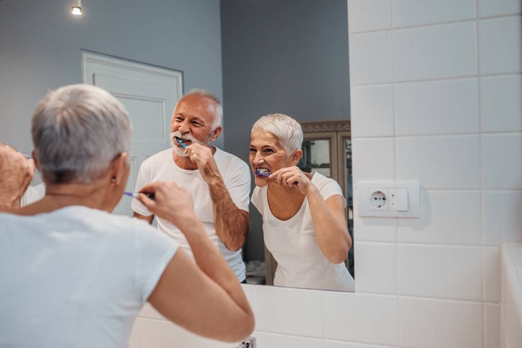 happy senior couple having fun while brushing teeth on their morning routine