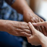 Family caregiver holds an elder's hands