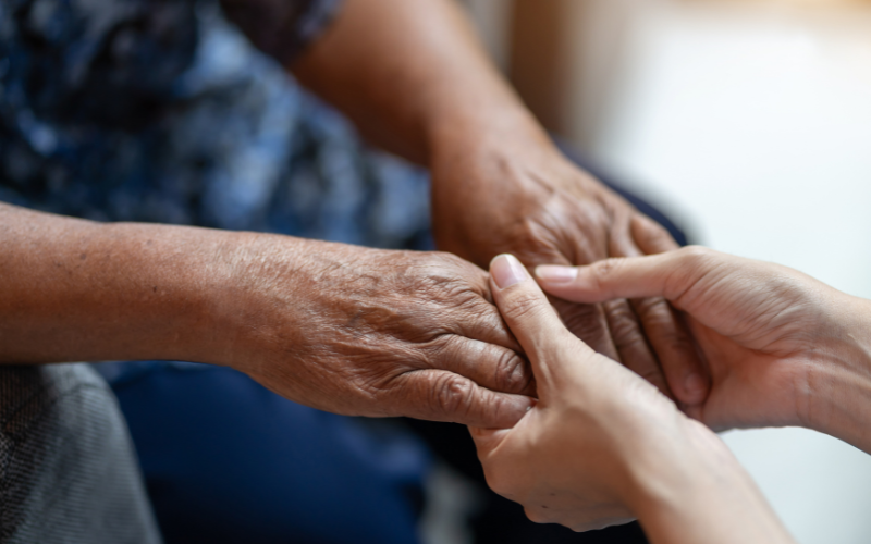 Family caregiver holds an elder's hands